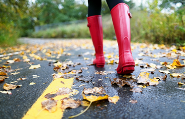 homeowner wearing red boots walking down their street that's covered with leaves
